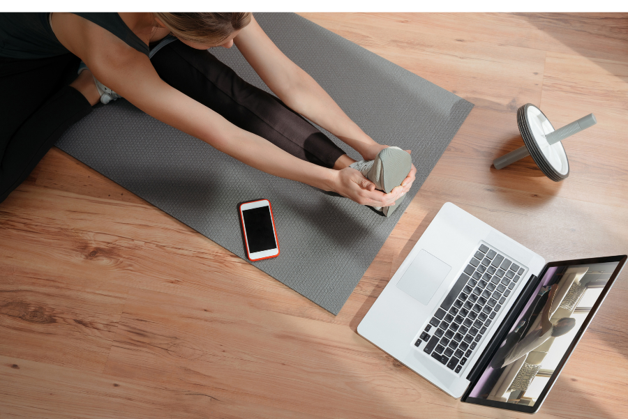 Frau macht Yoga vor dem Laptop